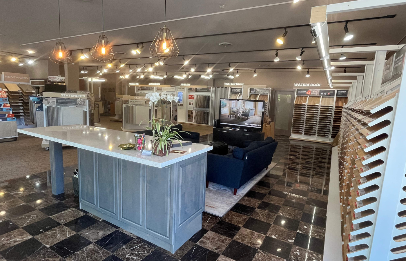 Entrance of Flooring America Seattle showroom featuring a modern counter, cozy seating, and well-lit displays of wood, tile, and waterproof flooring options in a welcoming, stylish setting.