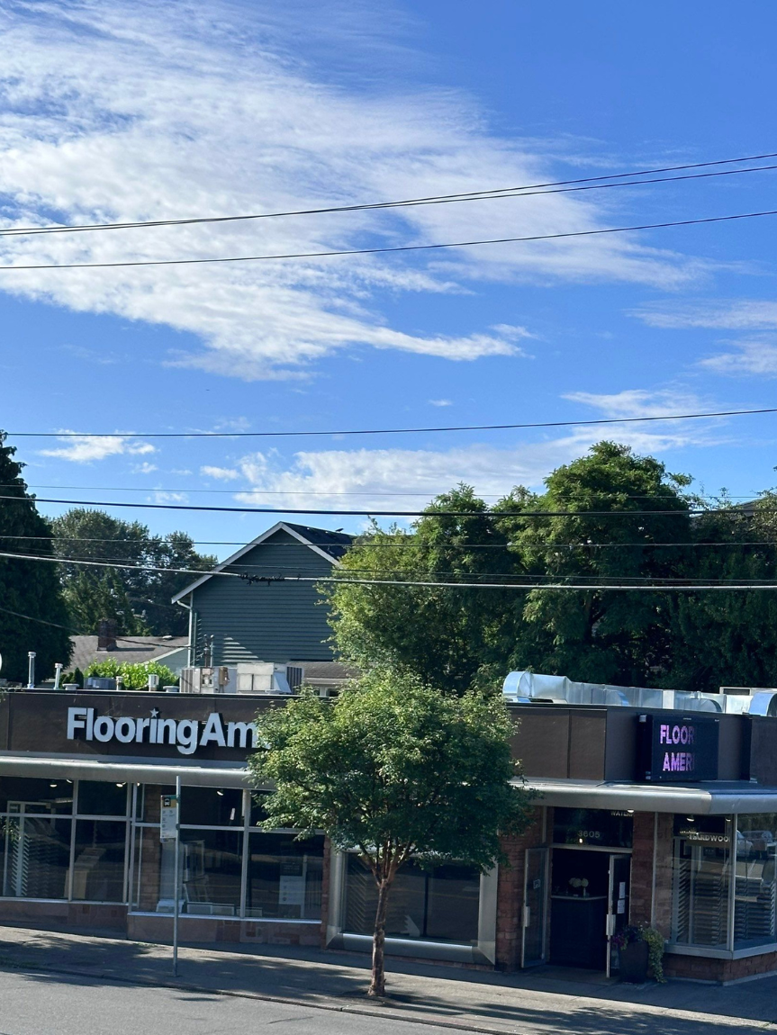 Flooring America, 3605 NE 45th St, Seattle, WA, with modern facade, large windows, and neon sign